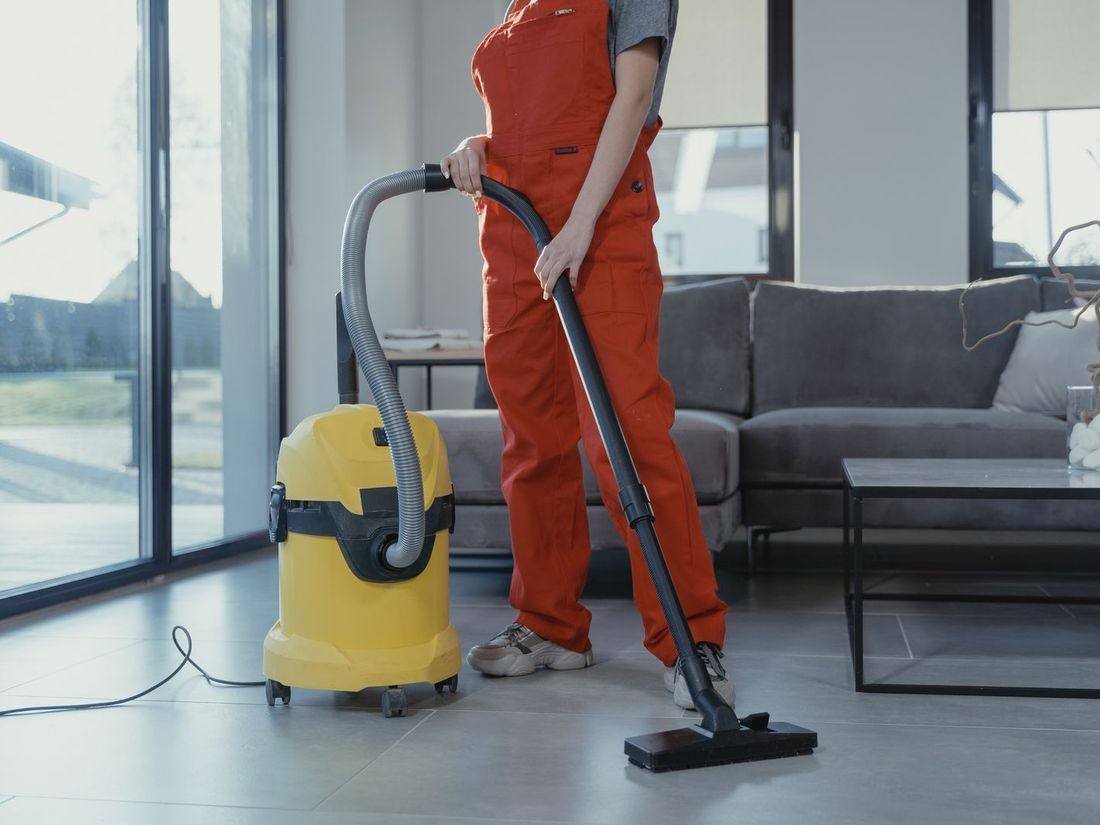 Professional cleaner vacuuming a living room