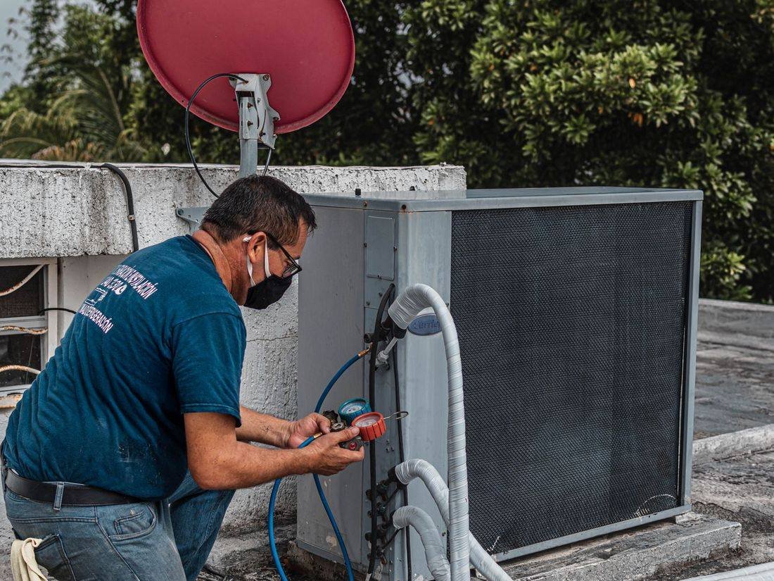 HVAC technician checking refrigerant pressure with gauges