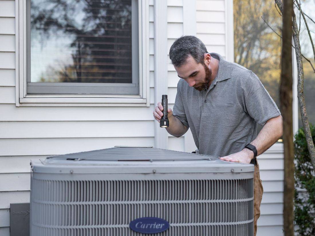 HVAC technician inspecting an outdoor air conditioning unit