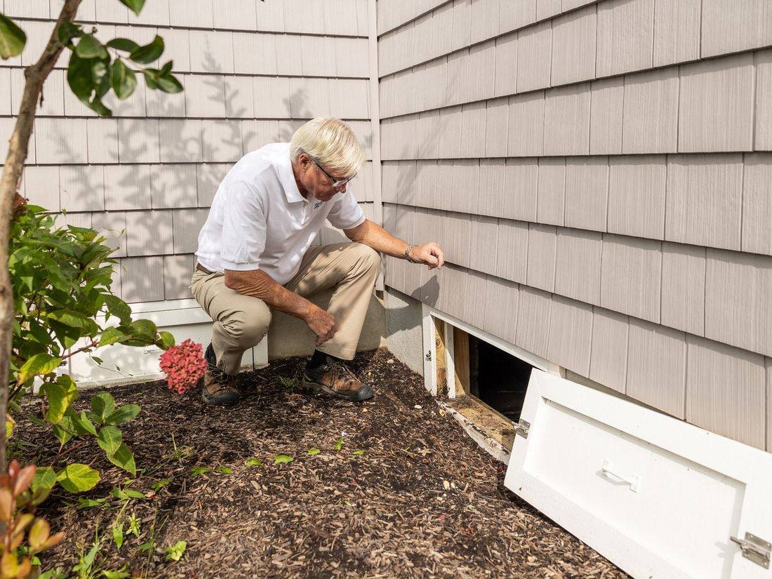Pest control technician inspecting the outside of a home