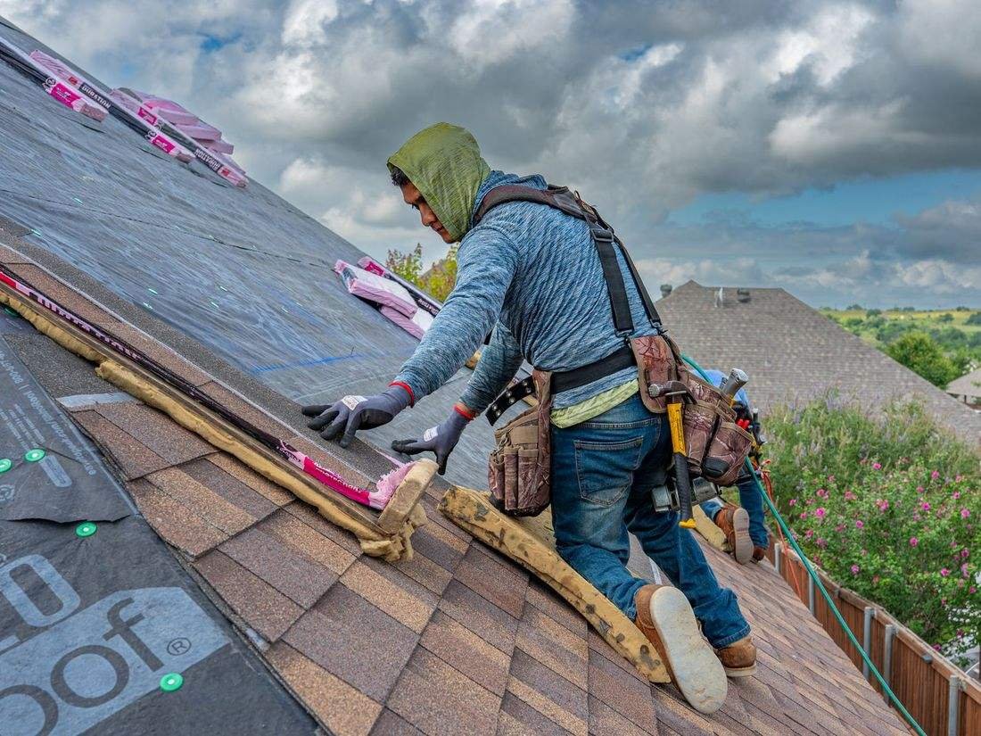 Roofing crew member working on a steep residential roof