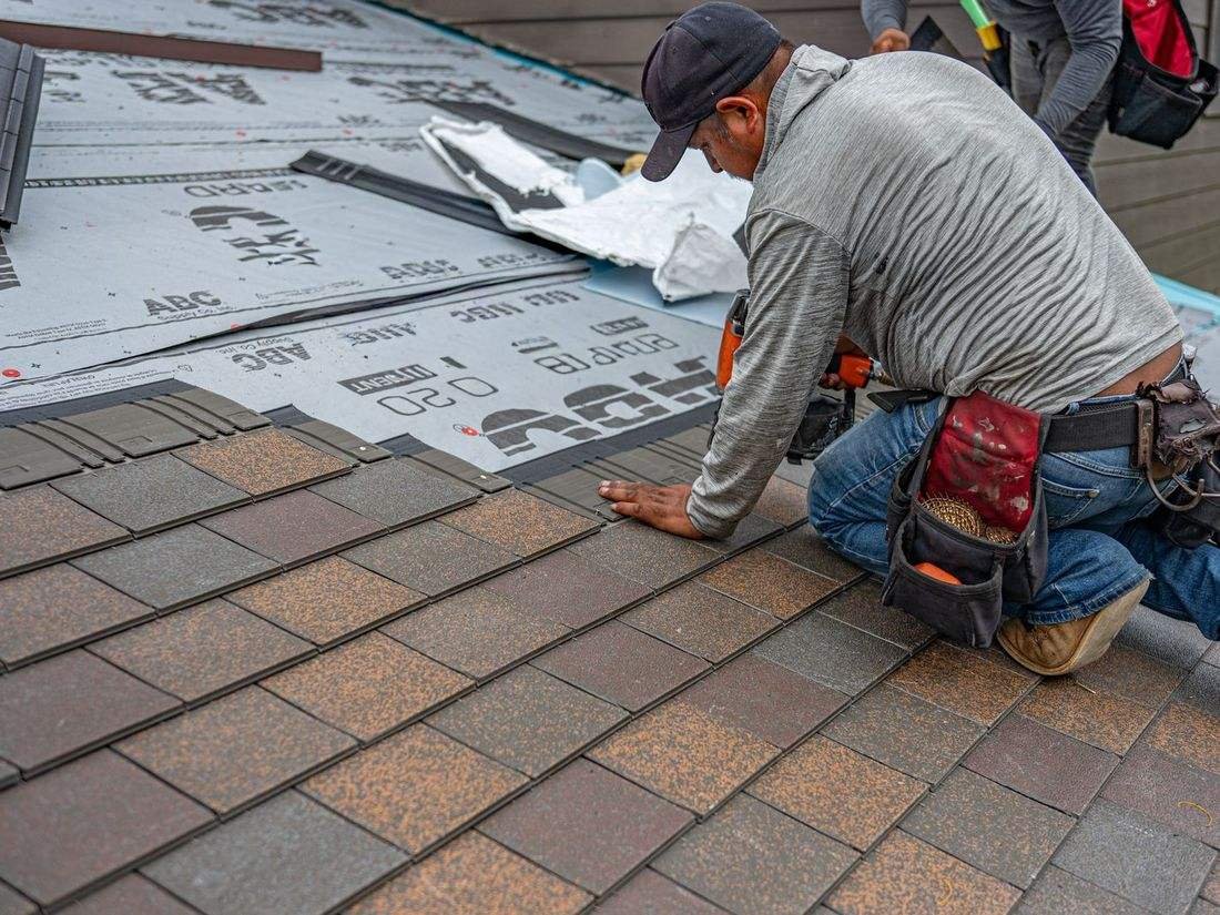 Roofer installing shingles on a residential roof