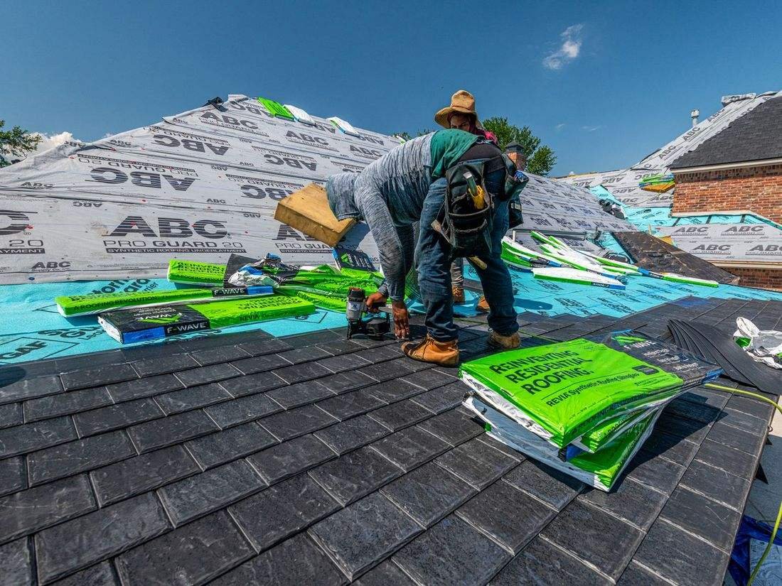 Roofers installing underlayment and shingles on a house